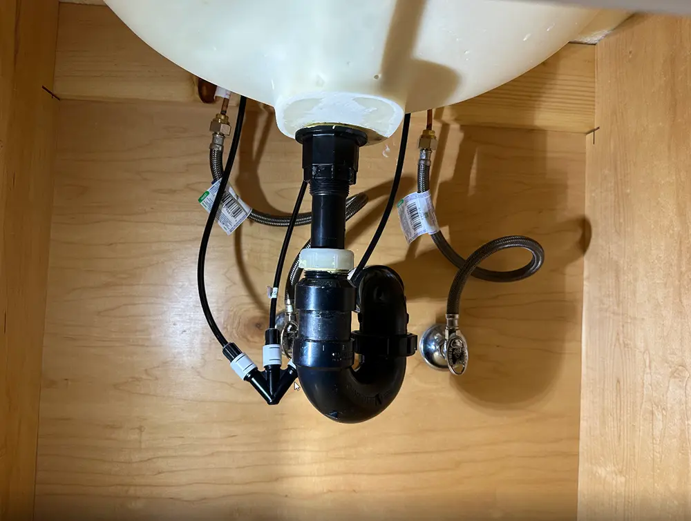 New bathroom sink plumbing with widespread faucet connections, angle stop valves, and P-trap assembly professionally installed for reliable, leak-free drainage.