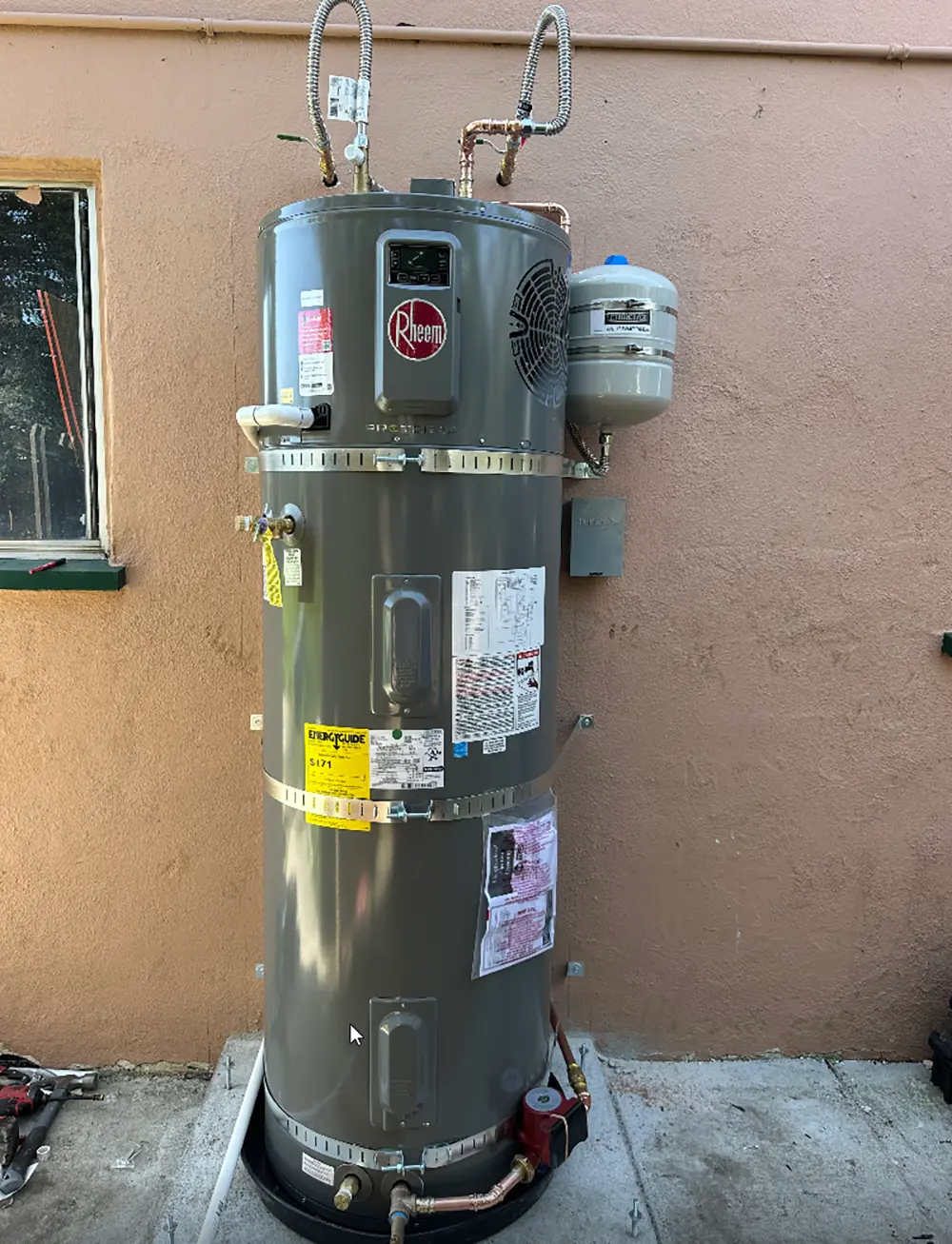 Rheem heat pump water heater professionally installed with expansion tank, recirculation pump, and dedicated hot and cold water lines for energy-efficient residential hot water.