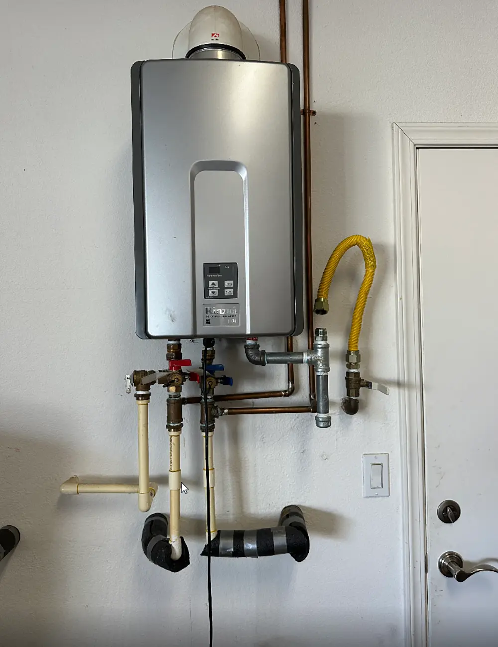 New high-capacity tankless water heater professionally installed with upgraded CPVC and copper piping, modified venting, and reconfigured water and gas connections.