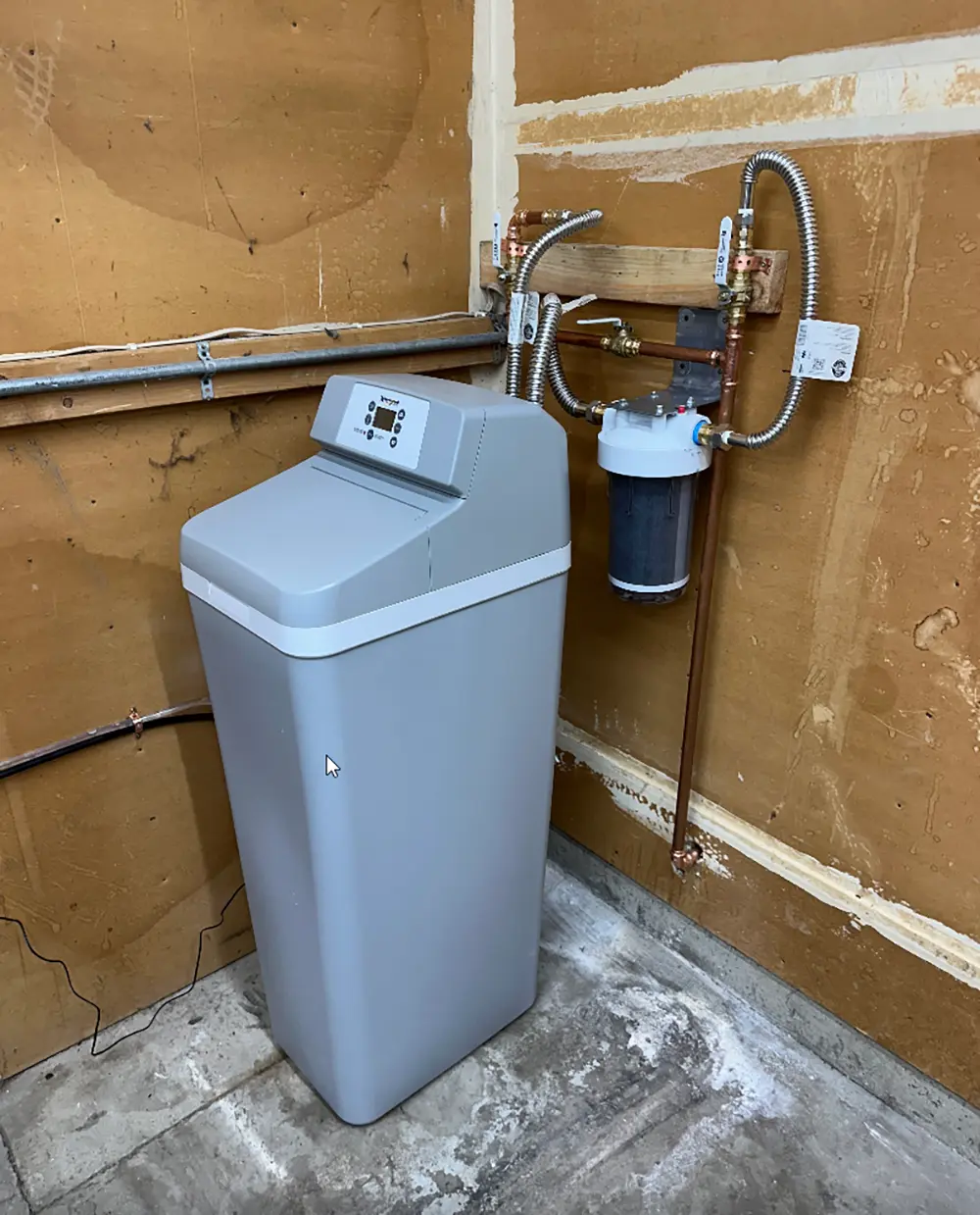 Compact whole house water softener installation with integrated brine tank, sediment pre-filter, three-valve bypass system, and professionally installed copper water lines.