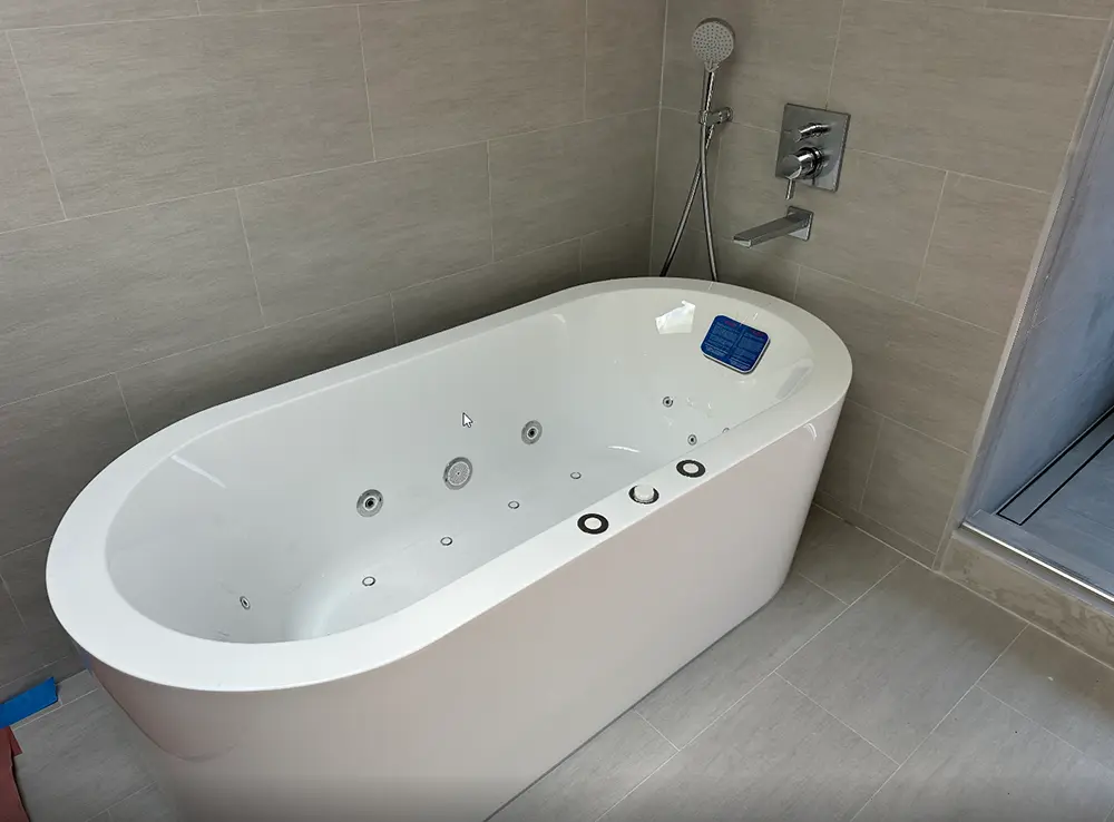 Modern freestanding soaking bathtub professionally installed with a level base, secure drain connection, and waterproof silicone sealing for a finished luxury bathroom.