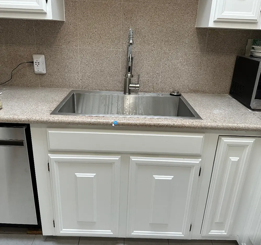 New kitchen sink, pull-down faucet, garbage disposal, and dishwasher connections professionally installed after lowering the drain line to improve kitchen drainage performance.