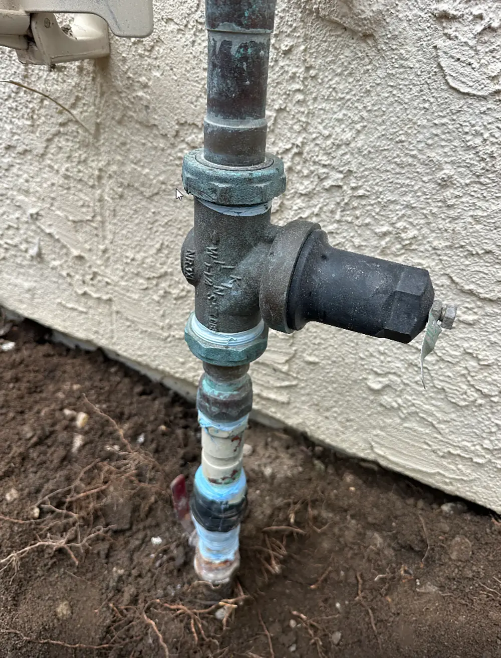 Old pressure reducing valve (PRV) with leaking connection and aging main water shut-off valve installed on a residential water service line before replacement.