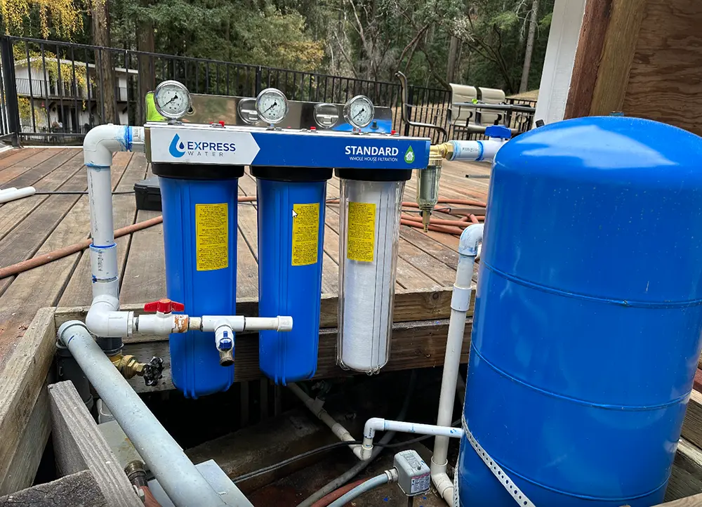 Three-stage whole house water filtration system installed on a private well water supply with sediment and carbon filters to improve water quality and eliminate odor.