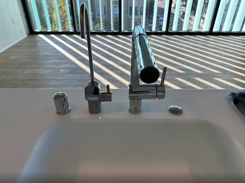 Modern kitchen sink faucet and air gap assembly connected to a newly installed kitchen drain system as part of a complete drain line replacement project.