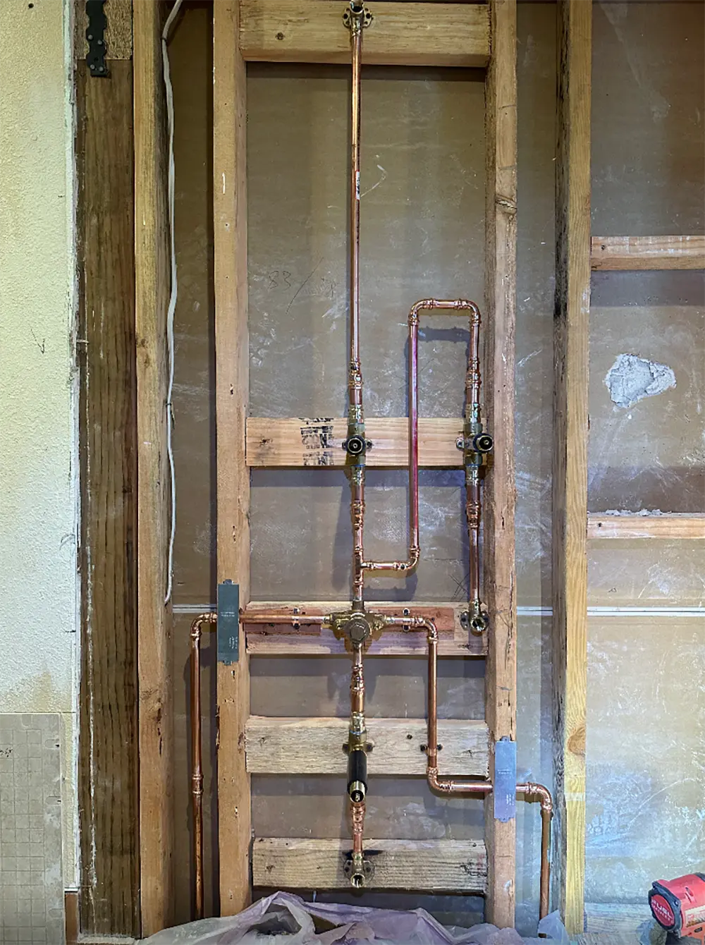 Double vanity plumbing rough-in with ProPress copper water supply lines, dual drain connections, and new angle stop valves installed inside bathroom wall framing